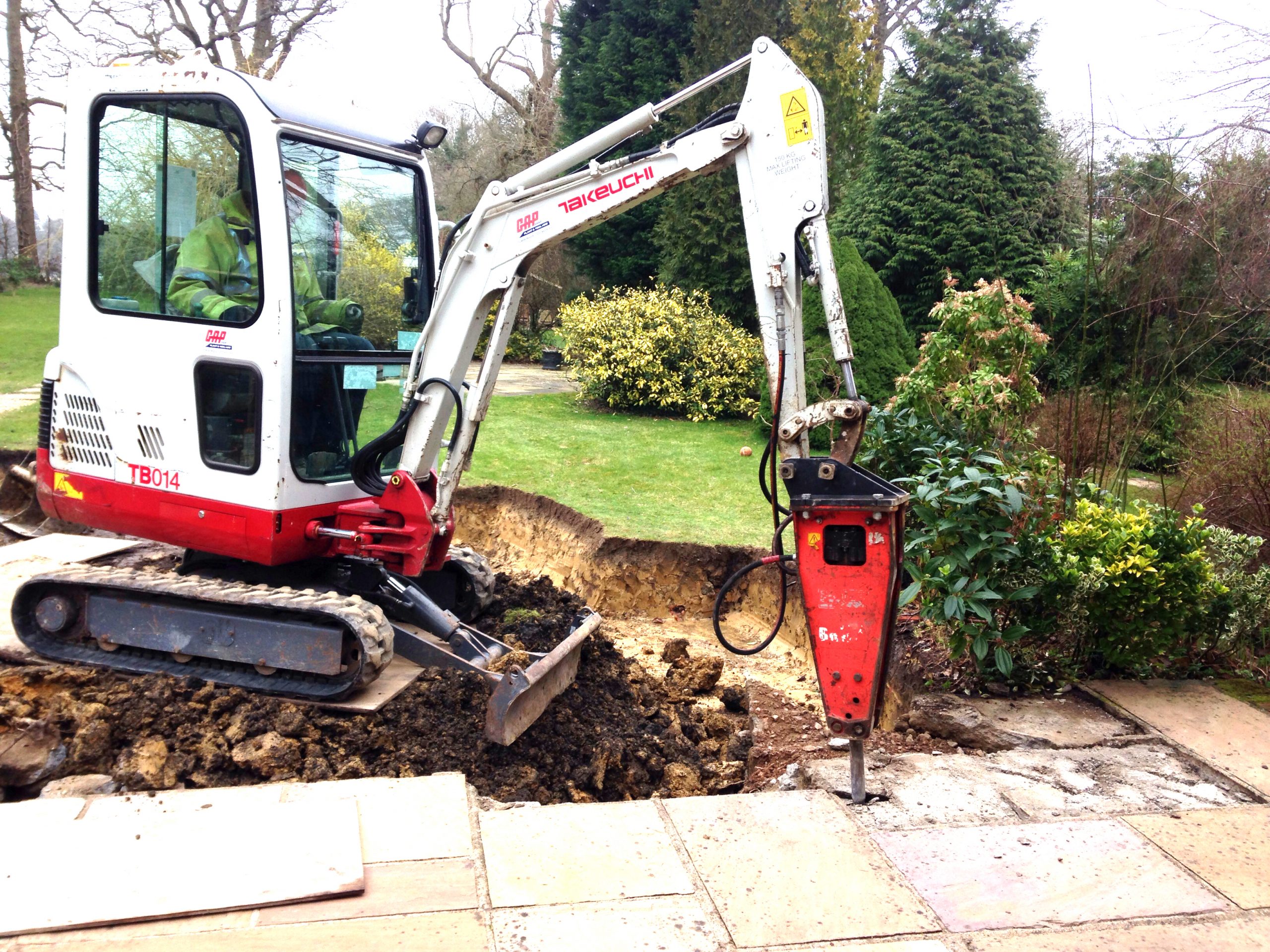 Small digger breaking up slabs in residential garden