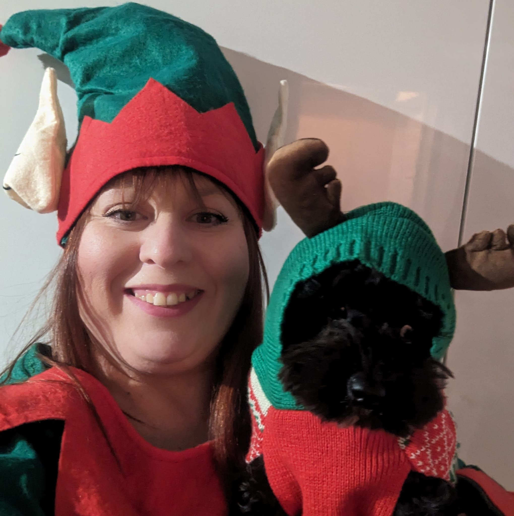A woman and her dog wearing Christmas outfits