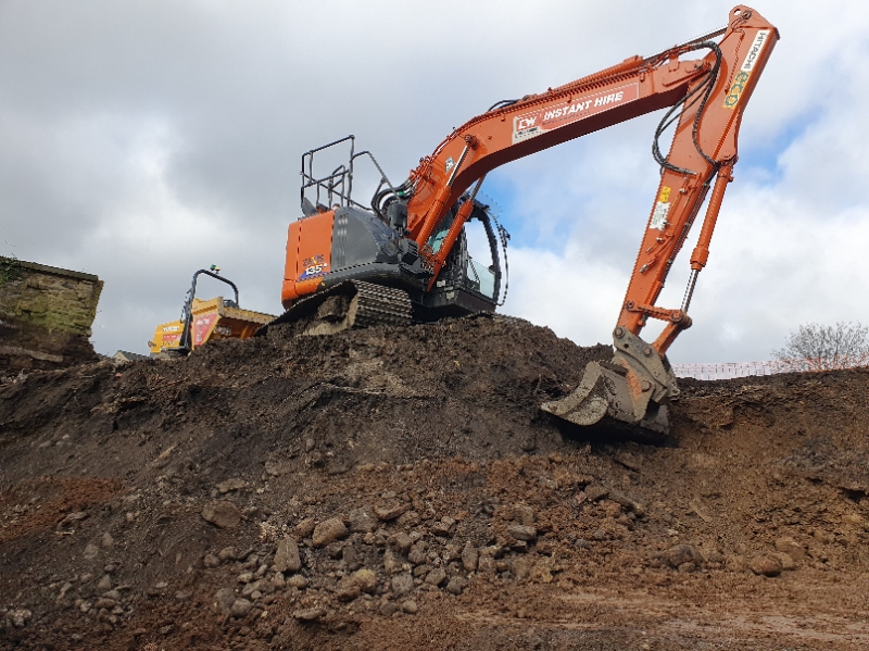 Excavator creating a stockpile of dug-up soils