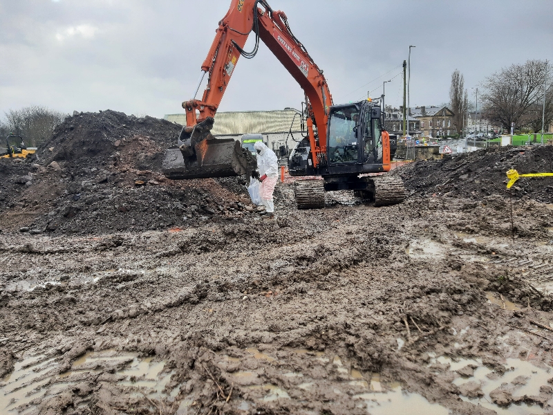 Man in hazmat suit hand picking asbestos from ground