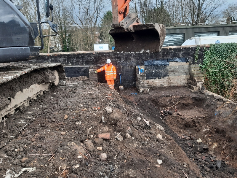 Excavator digging ground containing knotweed