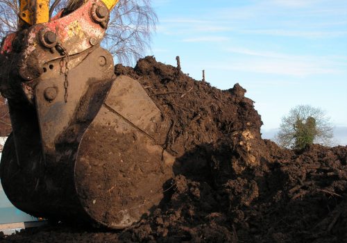 Large excavator bucket containing soil